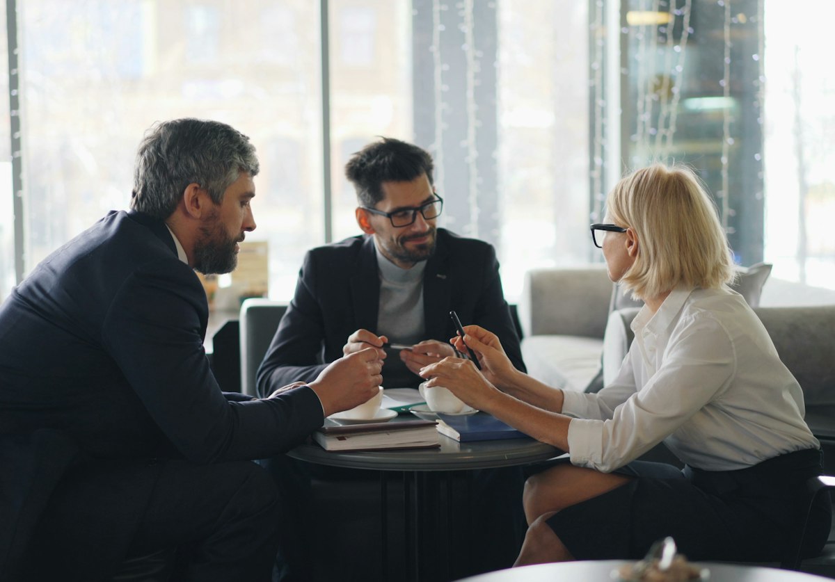 Três executivos conversando em sala envidraçada
