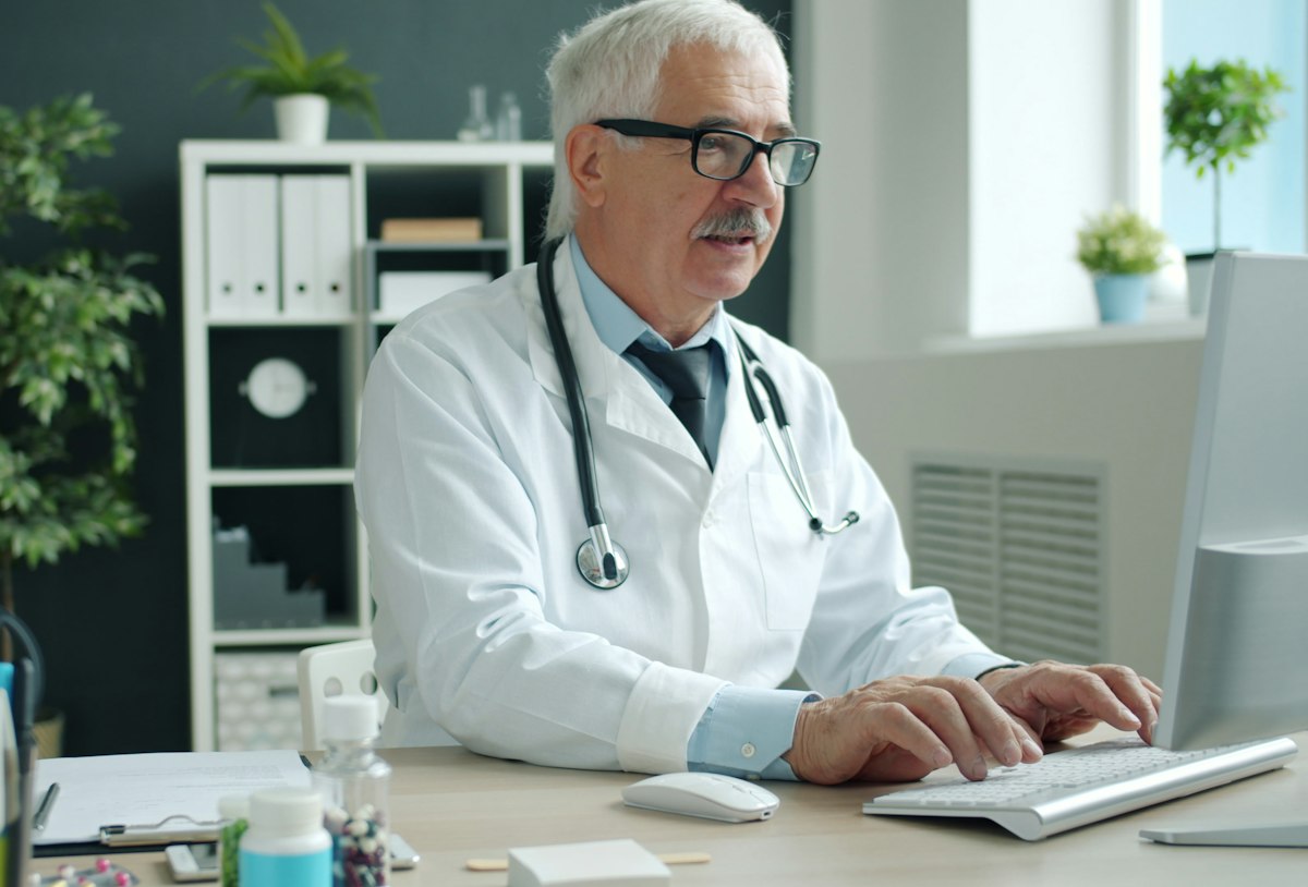 Médico trabalhando no computador do consultório
