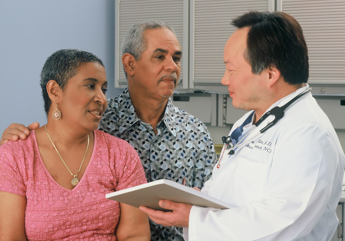 Médico conversando com casal de pacientes