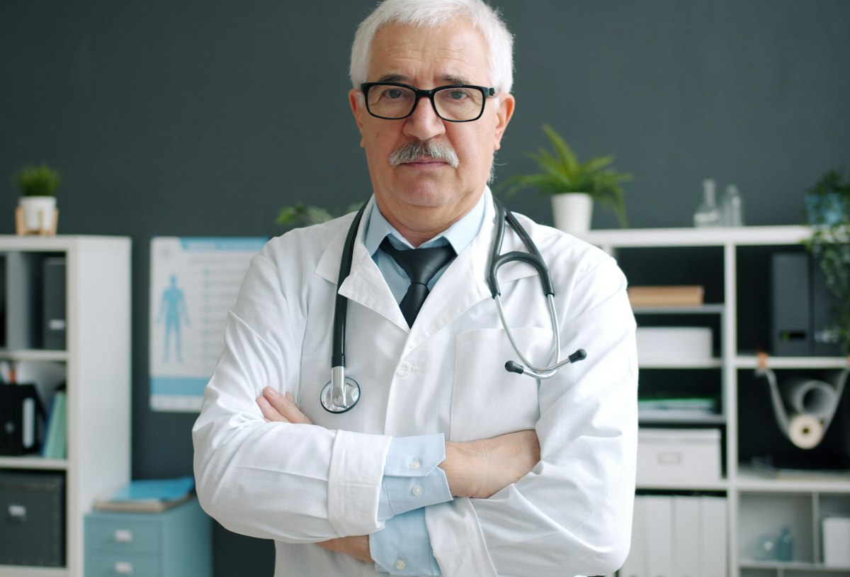 Médico de braços cruzados no consultório