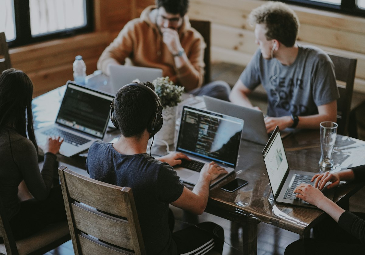 Colegas trabalhando com notebooks em mesa compartilhada