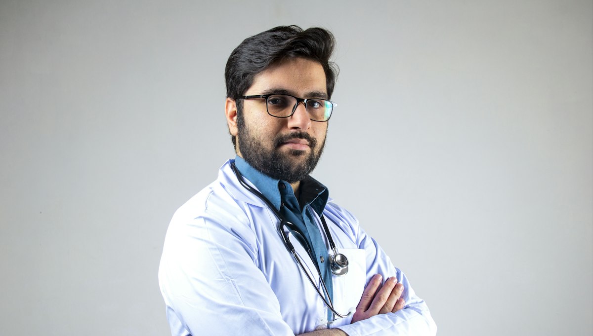 Médico de jaleco e braços cruzados