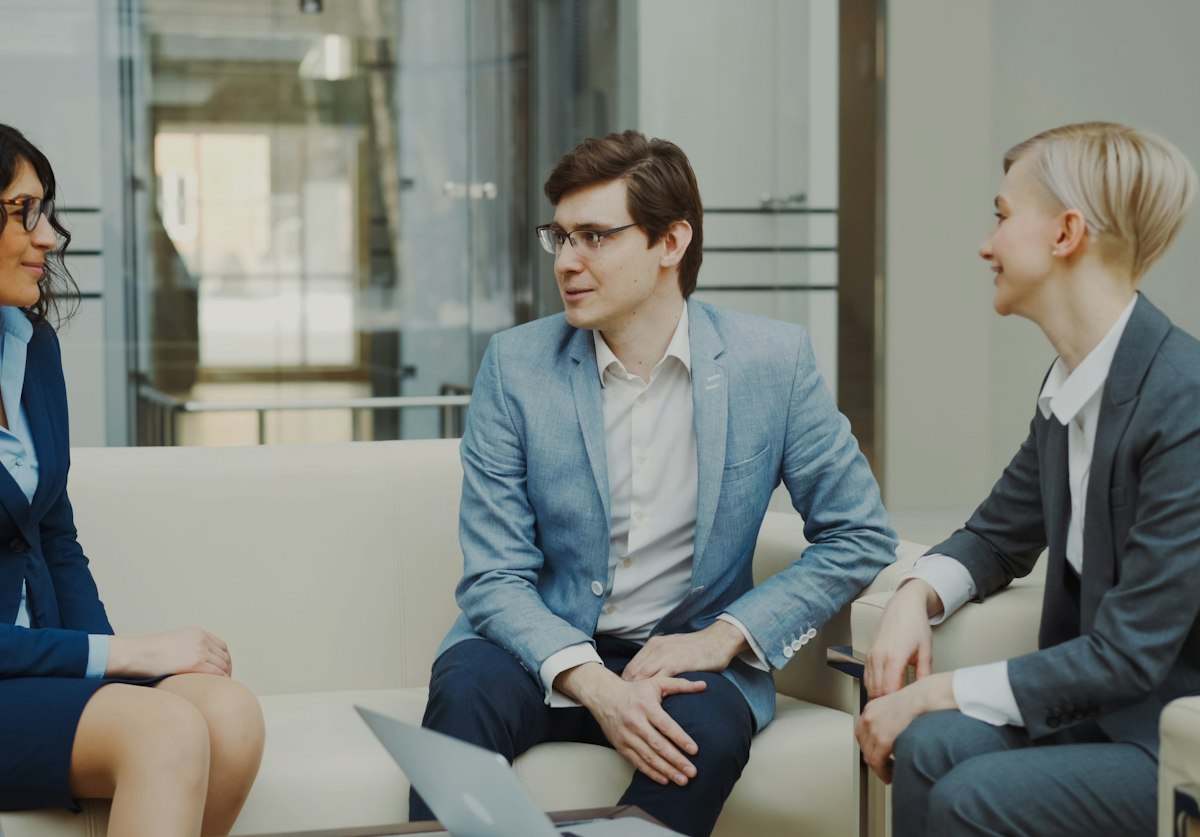 Três profissionais conversando no sofá do escritório